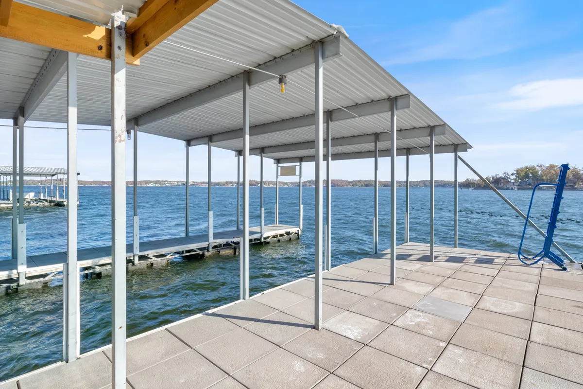 A serene waterfront scene featuring a dock structure with sturdy pillar supports extending into the water. The view captures the tranquil surface of the lake, inviting moments of boating, fishing, or relaxing right by the water's edge.
