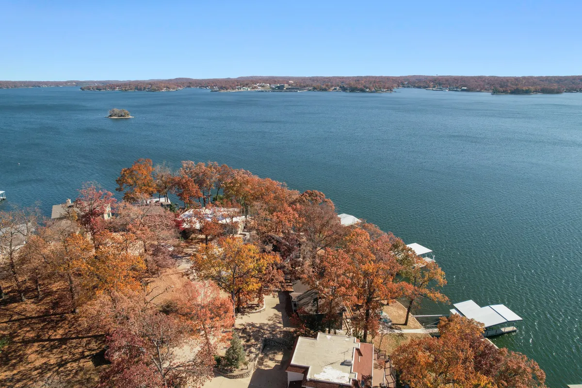 A sweeping view over the lake, dotted with docks, autumn foliage, and nearby houses. The image captures the essence of lakeside living with opportunities for boating, sunset cruises, and gathering on the water’s edge.