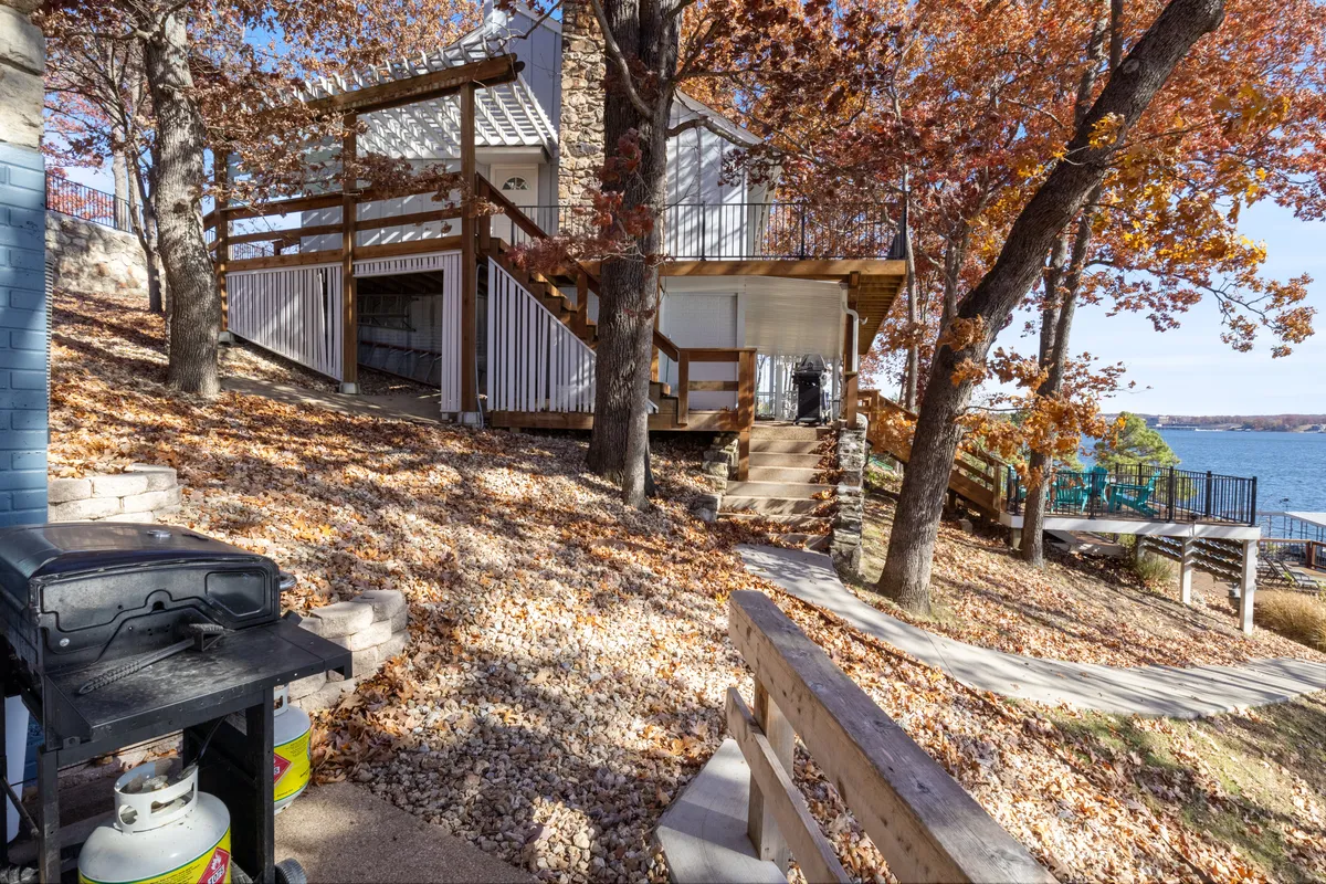 A cheerful, well-equipped wooden deck with a grill station and sweeping views of the waterfront, surrounded by autumn foliage. The setting is ideal for family barbecues, group gatherings, or simply soaking up the lakeside ambiance.