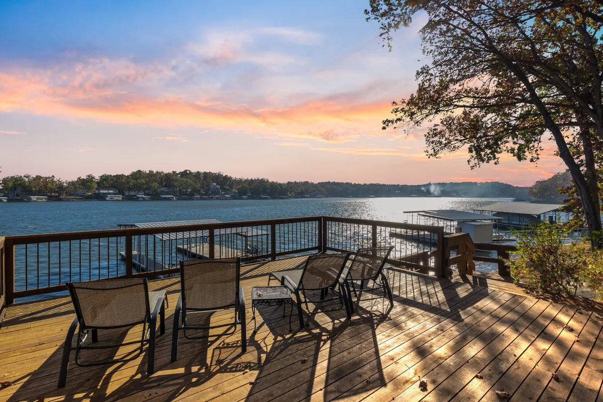 Deck chairs arranged to face a beautiful lake and a vibrant sunset sky, creating an inviting atmosphere for couples or small groups to relax, share a drink, or enjoy a quiet moment together.